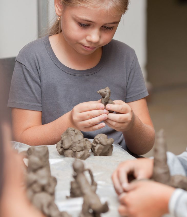 flicka skapar figurer i lera