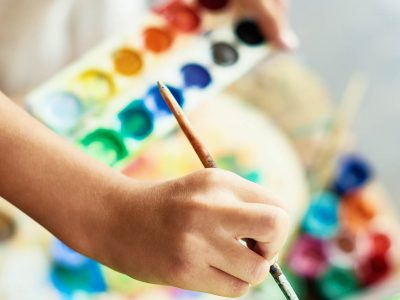Barn som håller i en pensel och målar med vattenfärger