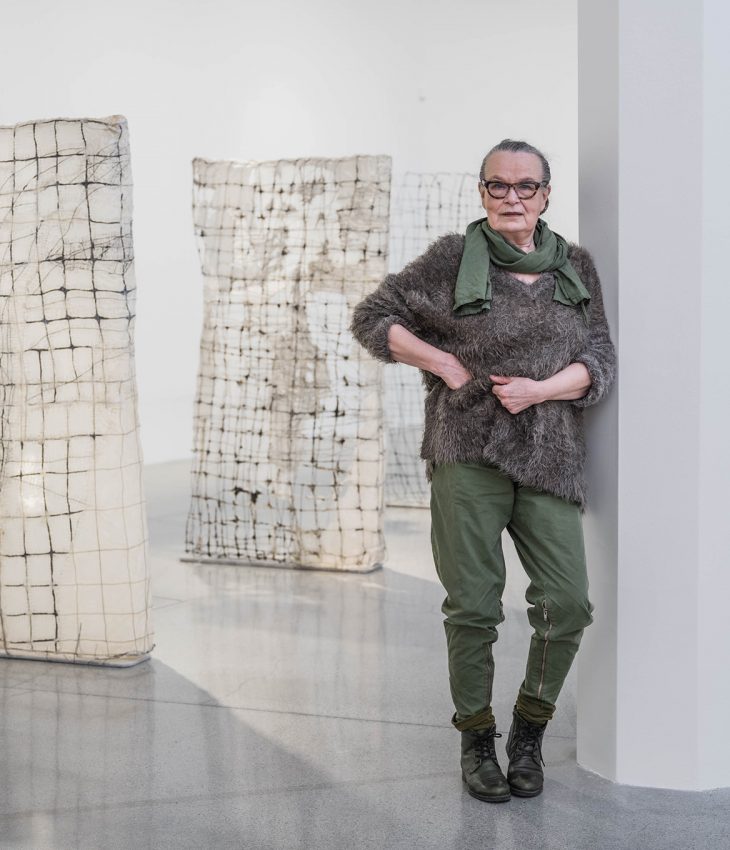 Konstnären Annika Liljedahl står framför skulpturer i sin utställning Väx till liv och lutar sig mot en pelare