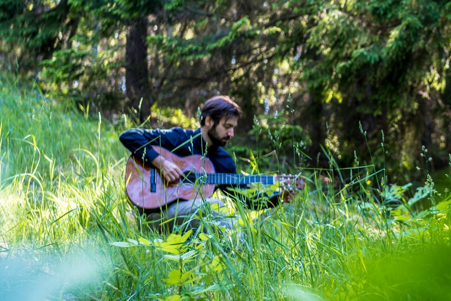 Foto av man som spelar på gitarr ute i naturen