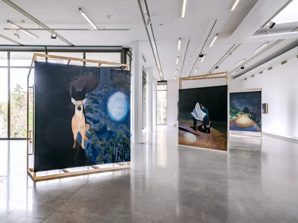 Utställningsvy med målade verk i en konsthall.