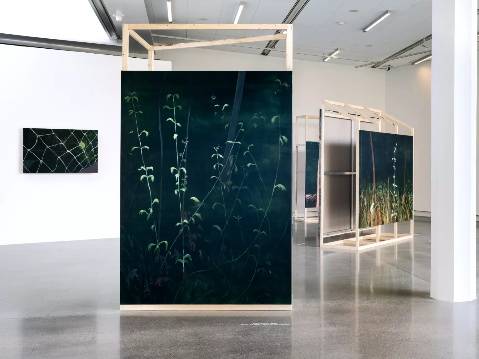Utställningsvy med målade verk i en konsthall.