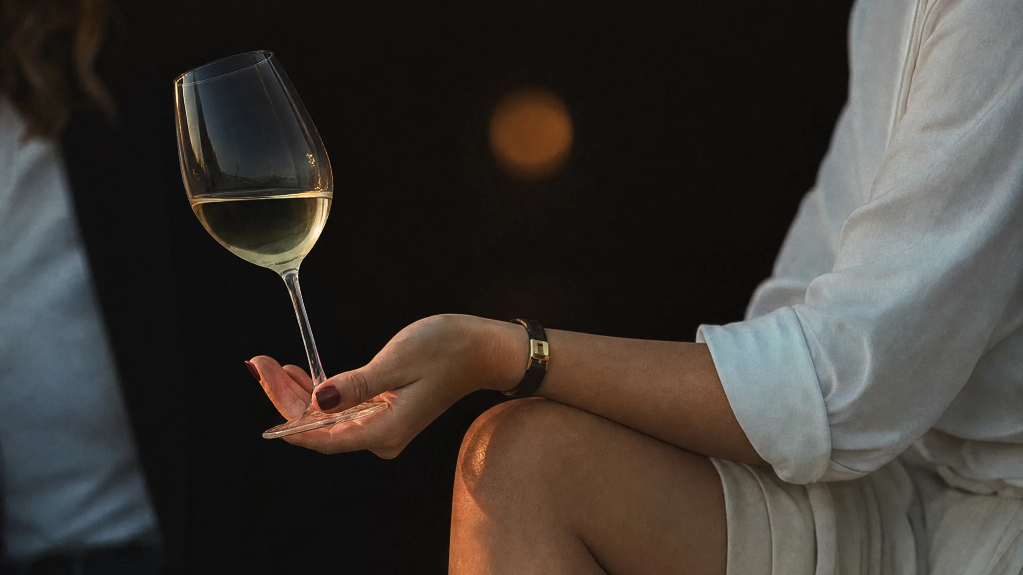 kvinna som sitter med ett glas vin i handen